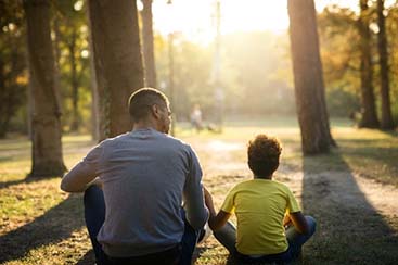 father-daughter-sitting-grass-park-enjoying-sunset-together_342744-975