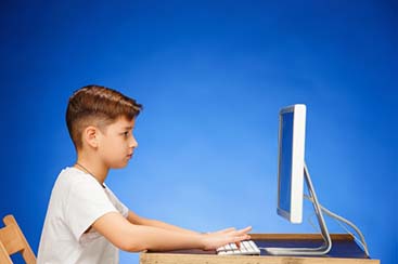 school-age-boy-sitting-front-monitor-laptop_155003-13706